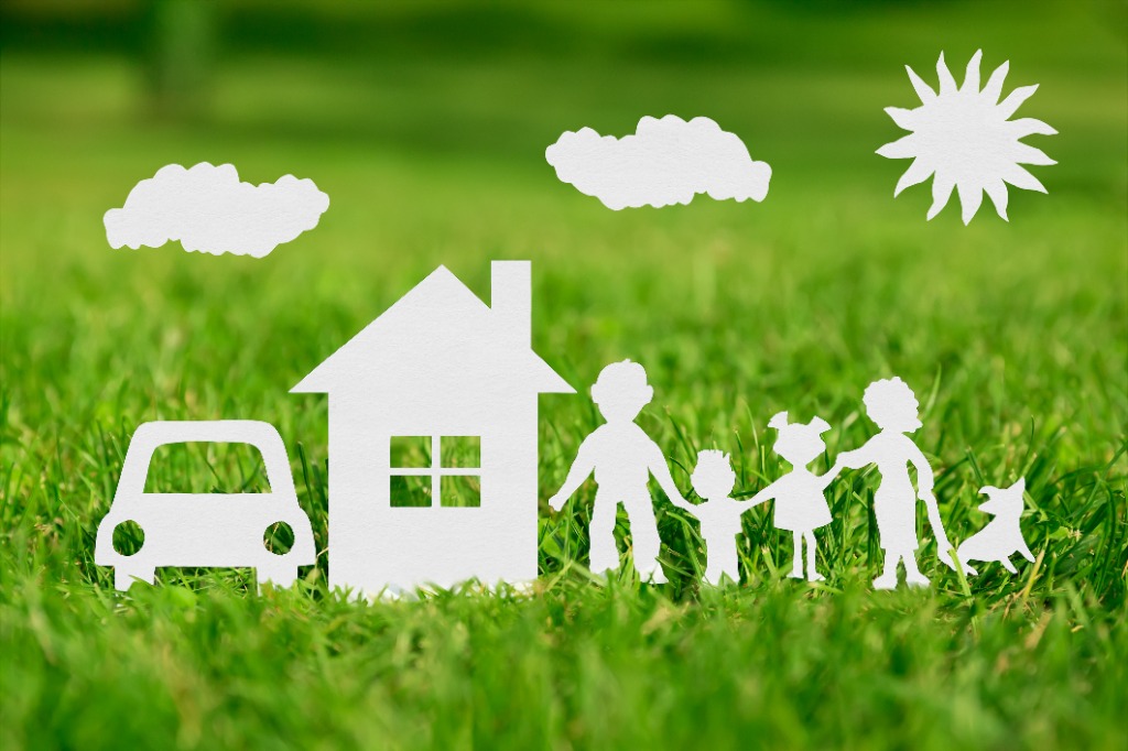 Paper cutout of family and home on green grass under the sun
